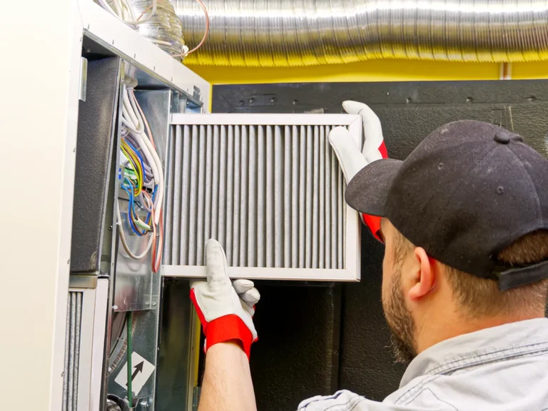 HVAC technician replacing a dirty air filter in an air handler