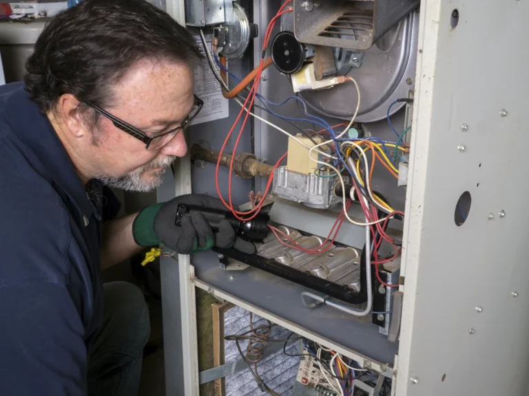 Technician inspecting the inside of a gas furnace with a flashlight